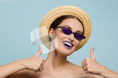 Image of Portrait of beautiful young woman with bright make-up isolated on blue studio background