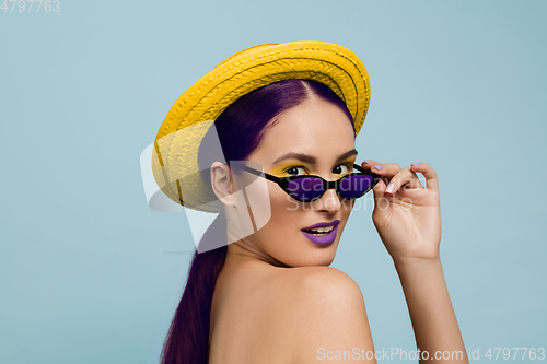 Image of Portrait of beautiful young woman with bright make-up isolated on blue studio background