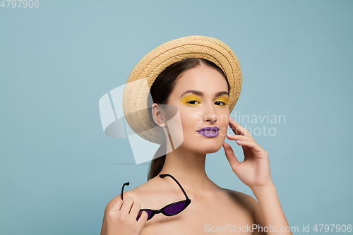 Image of Portrait of beautiful young woman with bright make-up isolated on blue studio background