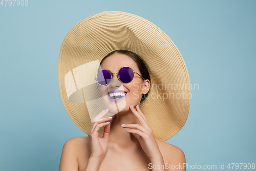 Image of Portrait of beautiful young woman with bright make-up isolated on blue studio background