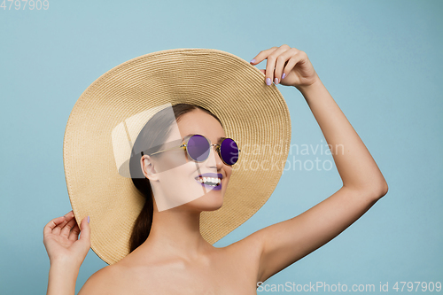 Image of Portrait of beautiful young woman with bright make-up isolated on blue studio background