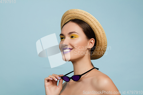 Image of Portrait of beautiful young woman with bright make-up isolated on blue studio background