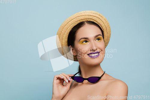 Image of Portrait of beautiful young woman with bright make-up isolated on blue studio background