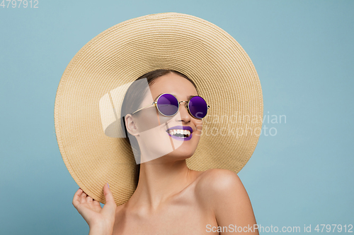 Image of Portrait of beautiful young woman with bright make-up isolated on blue studio background