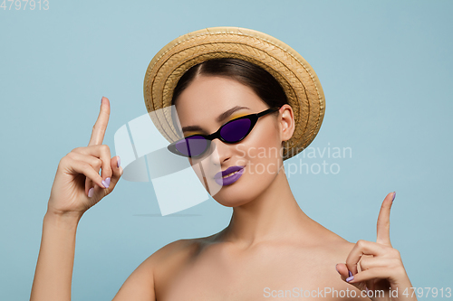 Image of Portrait of beautiful young woman with bright make-up isolated on blue studio background