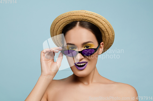 Image of Portrait of beautiful young woman with bright make-up isolated on blue studio background