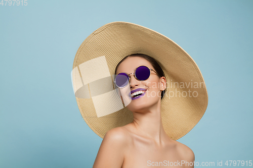 Image of Portrait of beautiful young woman with bright make-up isolated on blue studio background