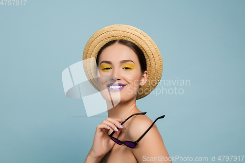 Image of Portrait of beautiful young woman with bright make-up isolated on blue studio background