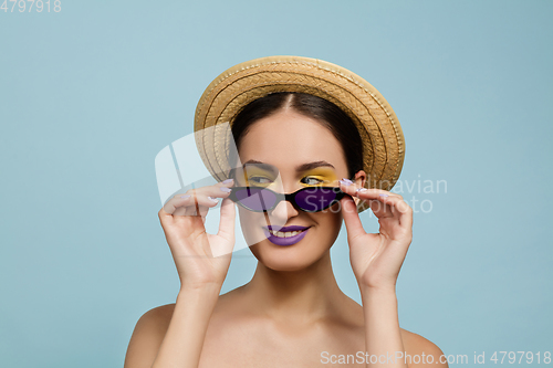 Image of Portrait of beautiful young woman with bright make-up isolated on blue studio background