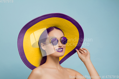 Image of Portrait of beautiful young woman with bright make-up isolated on blue studio background