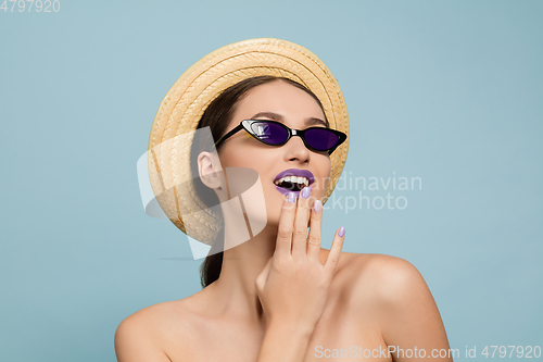 Image of Portrait of beautiful young woman with bright make-up isolated on blue studio background