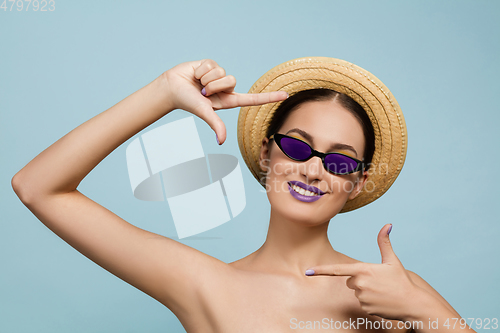 Image of Portrait of beautiful young woman with bright make-up isolated on blue studio background