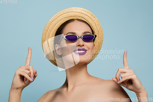 Image of Portrait of beautiful young woman with bright make-up isolated on blue studio background