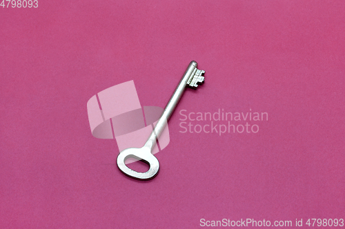 Image of Metal key on bright crimson paper 