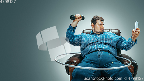 Image of Fat man sitting in a brown armchair, emotional watching TV