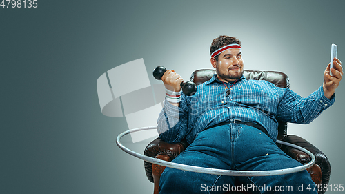 Image of Fat man sitting in a brown armchair, emotional watching TV