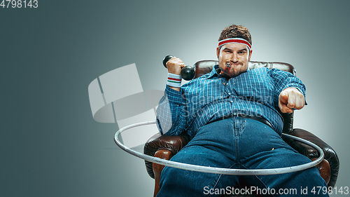 Image of Fat man sitting in a brown armchair, emotional watching TV