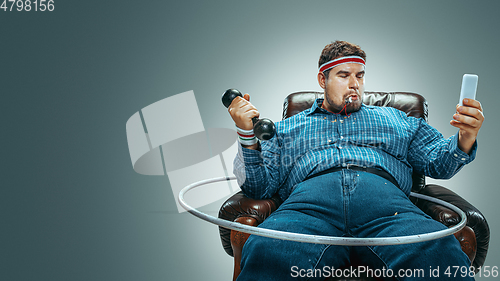 Image of Fat man sitting in a brown armchair, emotional watching TV