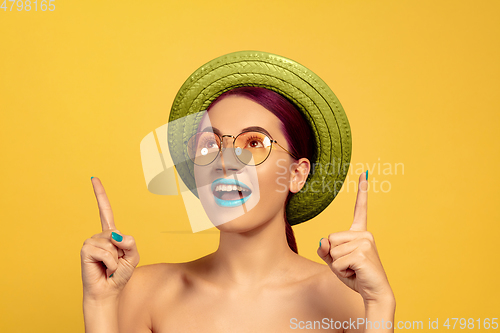 Image of Portrait of beautiful young woman with bright make-up isolated on yellow studio background