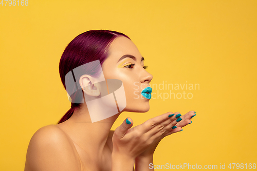 Image of Portrait of beautiful young woman with bright make-up isolated on yellow studio background