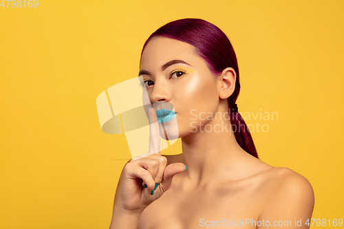 Image of Portrait of beautiful young woman with bright make-up isolated on yellow studio background