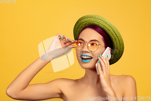 Image of Portrait of beautiful young woman with bright make-up isolated on yellow studio background