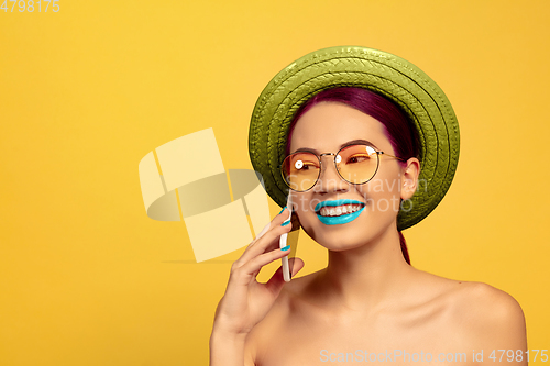 Image of Portrait of beautiful young woman with bright make-up isolated on yellow studio background