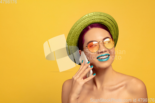 Image of Portrait of beautiful young woman with bright make-up isolated on yellow studio background