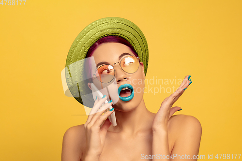 Image of Portrait of beautiful young woman with bright make-up isolated on yellow studio background