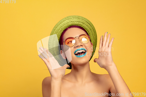 Image of Portrait of beautiful young woman with bright make-up isolated on yellow studio background