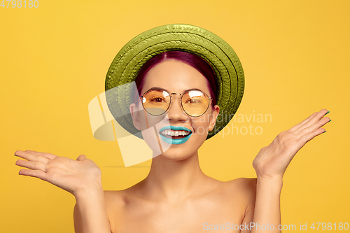 Image of Portrait of beautiful young woman with bright make-up isolated on yellow studio background