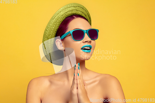 Image of Portrait of beautiful young woman with bright make-up isolated on yellow studio background