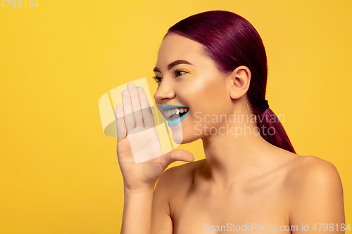 Image of Portrait of beautiful young woman with bright make-up isolated on yellow studio background