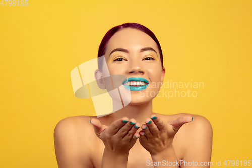 Image of Portrait of beautiful young woman with bright make-up isolated on yellow studio background