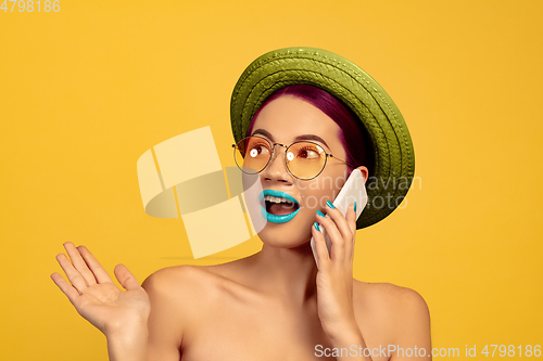 Image of Portrait of beautiful young woman with bright make-up isolated on yellow studio background