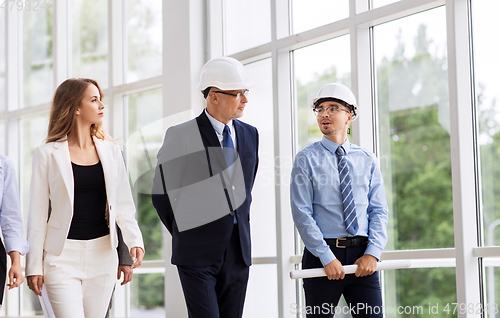 Image of business team in helmets walking along office