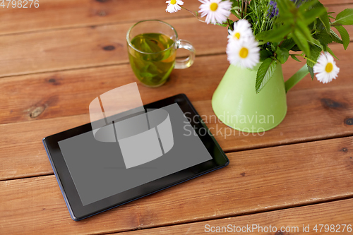 Image of tablet computer, herbal tea and flowers in jug
