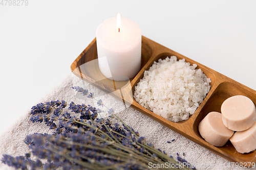 Image of sea salt, soap, candle and lavender on bath towel