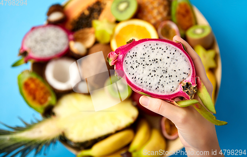 Image of hand holding half of dragon fruit over blue