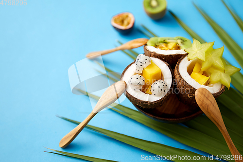 Image of mix of exotic fruits in coconut shells with spoons