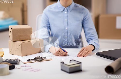 Image of close up of woman filling postal form at office