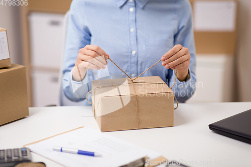 Image of woman packing parcel and tying rope at post office