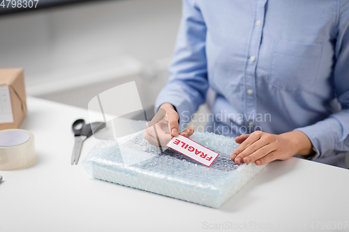 Image of woman sticking fragile mark to wrap at post office