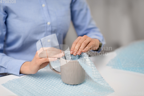 Image of woman packing mug to parcel box at post office