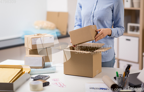 Image of woman packing parcel box at post office