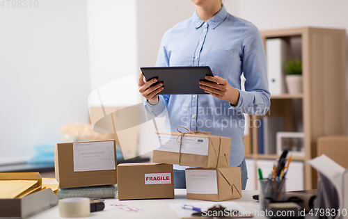 Image of woman with tablet pc and parcels at post office