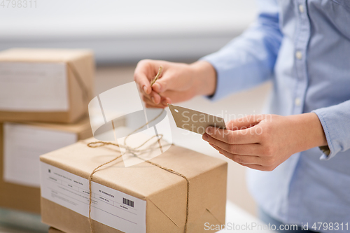 Image of woman packing parcel and tying tag at post office