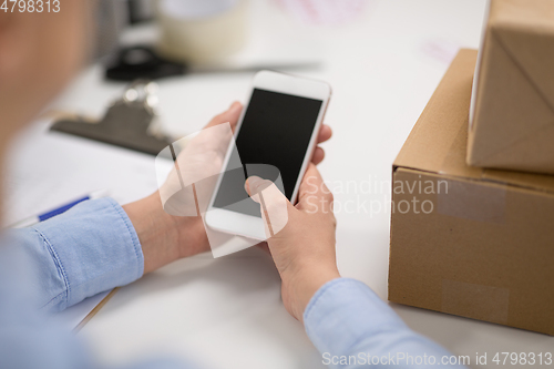 Image of hands with smartphone and parcels at post office