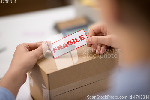 Image of woman sticking fragile mark to parcel box