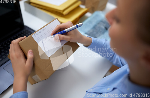 Image of close up of woman filling postal form at office